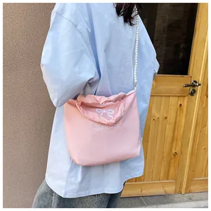 Detailed view of pink textured fabric bag with bow embroidery and pearl chain strap