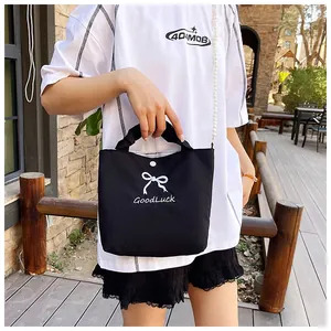 Close-up of black bow handbag with pearl chain strap and GoodLuck print detail