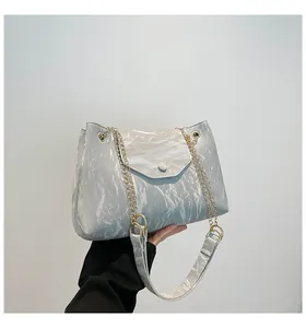 Detail der silbernen Tasche mit Knitteroptik und goldener Kette am Schultergurt