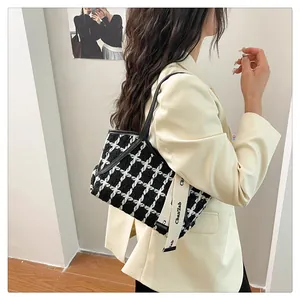 Details einer Schultertasche aus Tweed mit Karomuster, Lederbesatz und schickem Riemen
