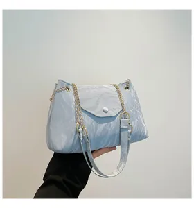 Details einer hellblauen Umhängetasche mit goldener Kette und seidiger Faltenstruktur