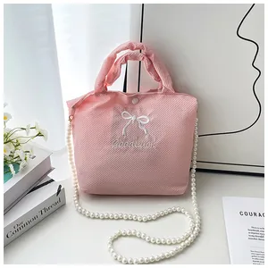 Detailed macro view of pink waffle textured fabric bag with white bow embroidery and pearls