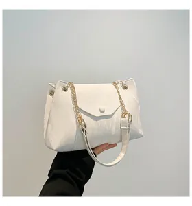 Detail der weißen Handtasche mit Faltenstruktur, Goldkette und Magnetverschluss