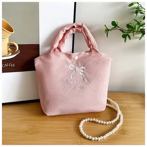 Close-up of pink fabric handbag featuring white bow embroidery and Good Luck lettering