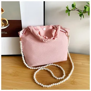 Detail of pink woven fabric handbag featuring a faux pearl chain and snap button closure
