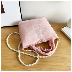 Detail of pink waffle texture handbag with bow embroidery and pearl chain strap