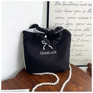 Macro view of black waffle weave handbag featuring pearl chain and GoodLuck embroidery