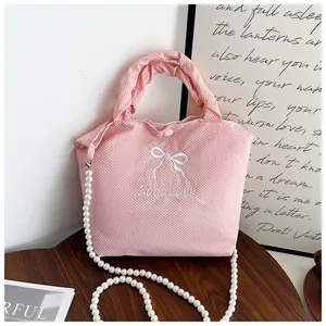 Detailed view of pink quilted fabric handbag with pearl chain and bow embroidery