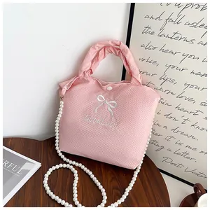 Detail of pink waffle texture bag with pearl strap, bow embroidery and snap button closure