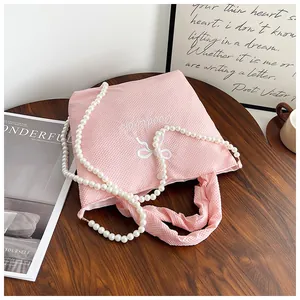 Detail of pink waffle texture handbag with bow embroidery and pearl chain strap