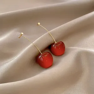 Boucles d'oreilles cerises tendance avec perles rouges brillantes et crochets dorés sur satin