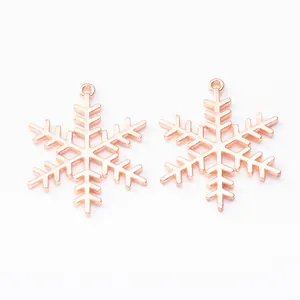 Vista macro di due ciondoli a fiocco di neve in oro rosa con design cavo per gioielli
