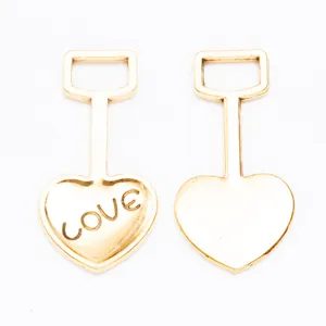 Detail van gouden hartvormige hangers met LOVE-gravure en rechthoekige metalen lussen