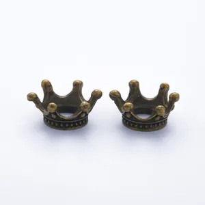 Detailed macro view of two vintage bronze alloy crown charms for DIY jewelry making