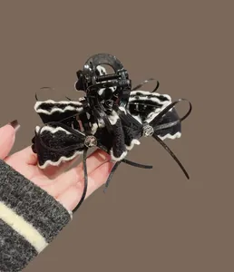 Dettaglio di una grande molletta per capelli con fiocco di velluto e strass in mano