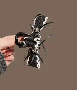 Dettaglio del fermaglio per capelli con fiocco di velluto, strass e trama in maglia
