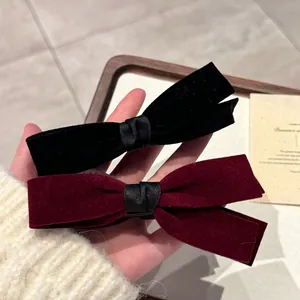 Détails de pinces à cheveux élégantes en velours noir et bordeaux tenues à la main pour coiffure
