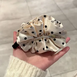 Détail de la barrette à nœud crème avec pois noirs, perles blanches et pendentif doré