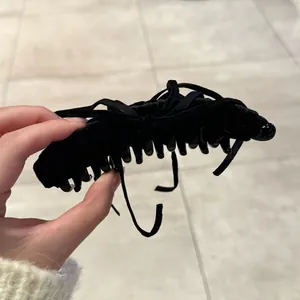 Vue détaillée d'une pince à cheveux en velours noir avec nœud et rubans croisés élégants