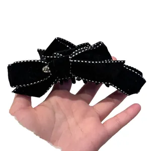 Pinza para el pelo con lazo de terciopelo negro costuras blancas y detalle de metal oro