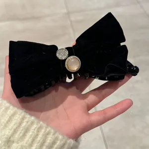Détail de la pince banane en velours noir à double nœud avec perle et strass
