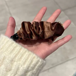 Barrette banane plissée en velours marron foncé avec détail anneau doré élégant en main