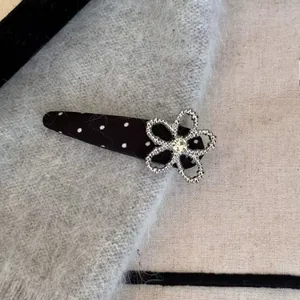 Dettaglio di fermaglio per capelli con fiore di strass argento e motivo a pois