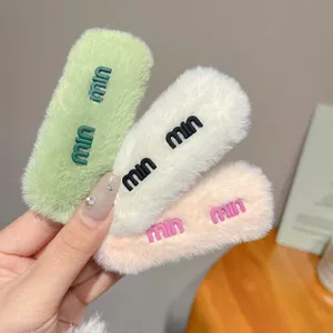 Dettaglio di fermagli per capelli in peluche verde, avorio e rosa con logo 3D in rilievo