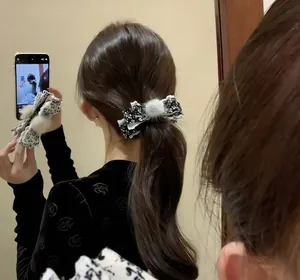 Détail de la pince à cheveux nœud floral avec pompon gris et dentelle élégante