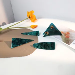 Elegantes 4-teiliges dunkelgrünes Marmor-Haarclip-Set mit goldenen Details auf weißem Tisch