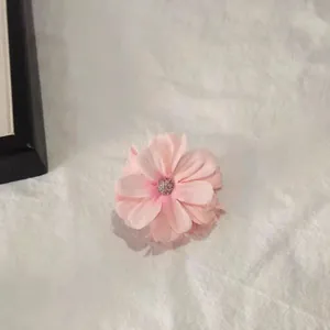 Close-up of pink fabric floral hair claw with rhinestone center on white tablecloth