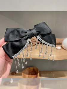 Detail einer eleganten schwarzen Satinschleife mit glitzernden Strass-Fransenquasten