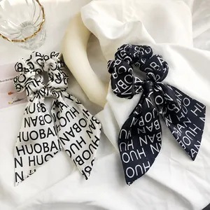 Close-up of leopard pattern scrunchies with ribbons in black and white satin fabric