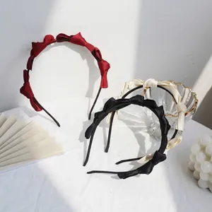 Trois serre-têtes en velours rouge, noir et crème avec détails de nœuds élégants
