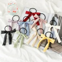 Flat lay of colorful satin bow hair scrunchies on a magazine with nine elegant color options