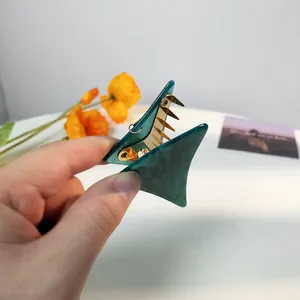 Detailansicht einer Hand, die die dunkelgrüne geometrische Haarklammer hält