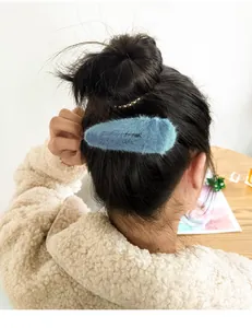 Close-up of soft blue plush hair clip worn by a model in a warm autumn winter setting