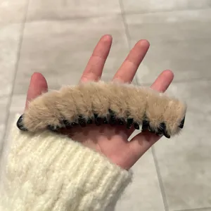 Détail d'une pince banane en peluche marron clair avec des dents en plastique noir