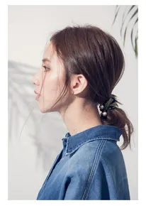 Detailed view of elegant floral ribbon hair tie with large white pearls on a model's hair