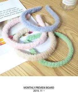 Detailansicht von vier flauschigen Haarreifen in Pastellfarben auf einem Holztisch