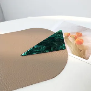 Nahaufnahme einer grünen Marmor-Haarklammer mit Goldglitzer auf Leder-Hintergrund