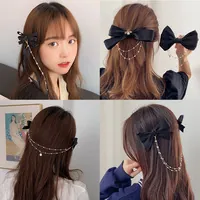 Detail of black silk bow hair clip with pearl tassels and gold metal chain fringe