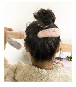 Detail view of plush faux fur hair clips in pink and beige worn on a bun hairstyle