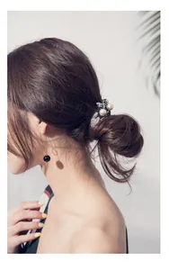 Close-up of elegant pearl scrunchie and black bead drop earrings worn by a model