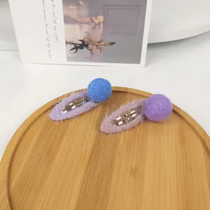 Detail view of winter mohair BB hair clips with handmade felt balls on a wooden tray