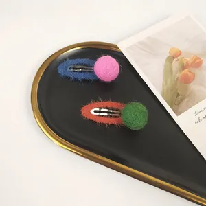Detail of colorful mohair hair clips with fuzzy wool balls in a decorative heart tray