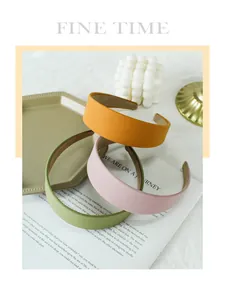 Detailed view of three solid color fabric headbands in mustard yellow, green and pink