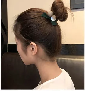 Élastique à cheveux avec nœud vert foncé et perles sur un chignon moderne