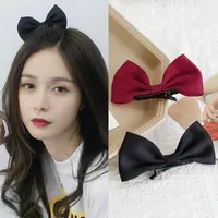 Close-up of elegant canvas bow hair clips in black and burgundy with long duckbill clips