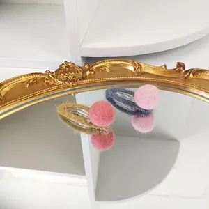 Detail of wool felt ball hair clips on a vintage mirror reflecting soft textures and colors